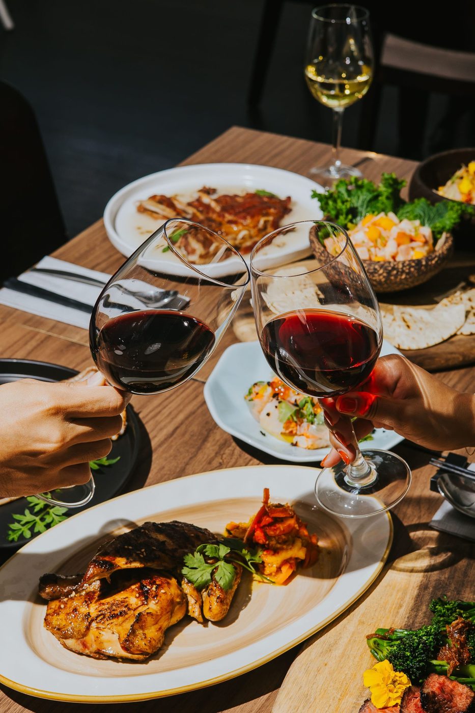 Guests toasting red wine over open-flame grill dishes at Botanico, The Summerhouse Seletar