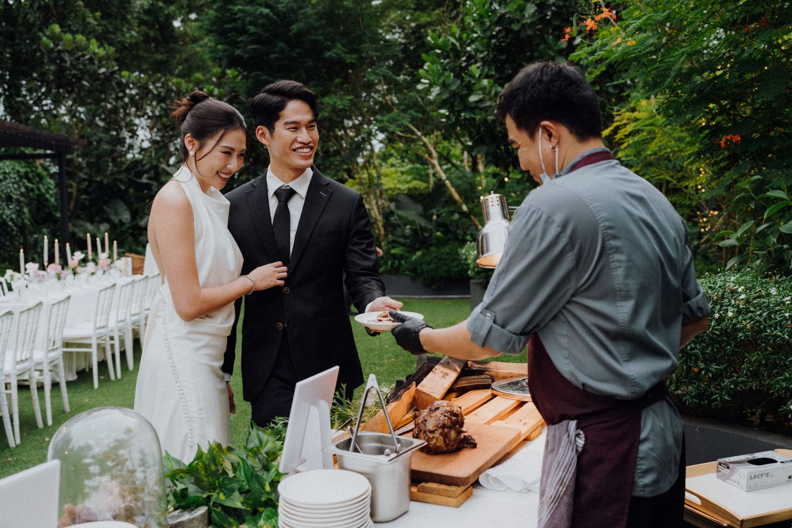 Newlyweds at the live carving station during a garden wedding reception at The Summerhouse